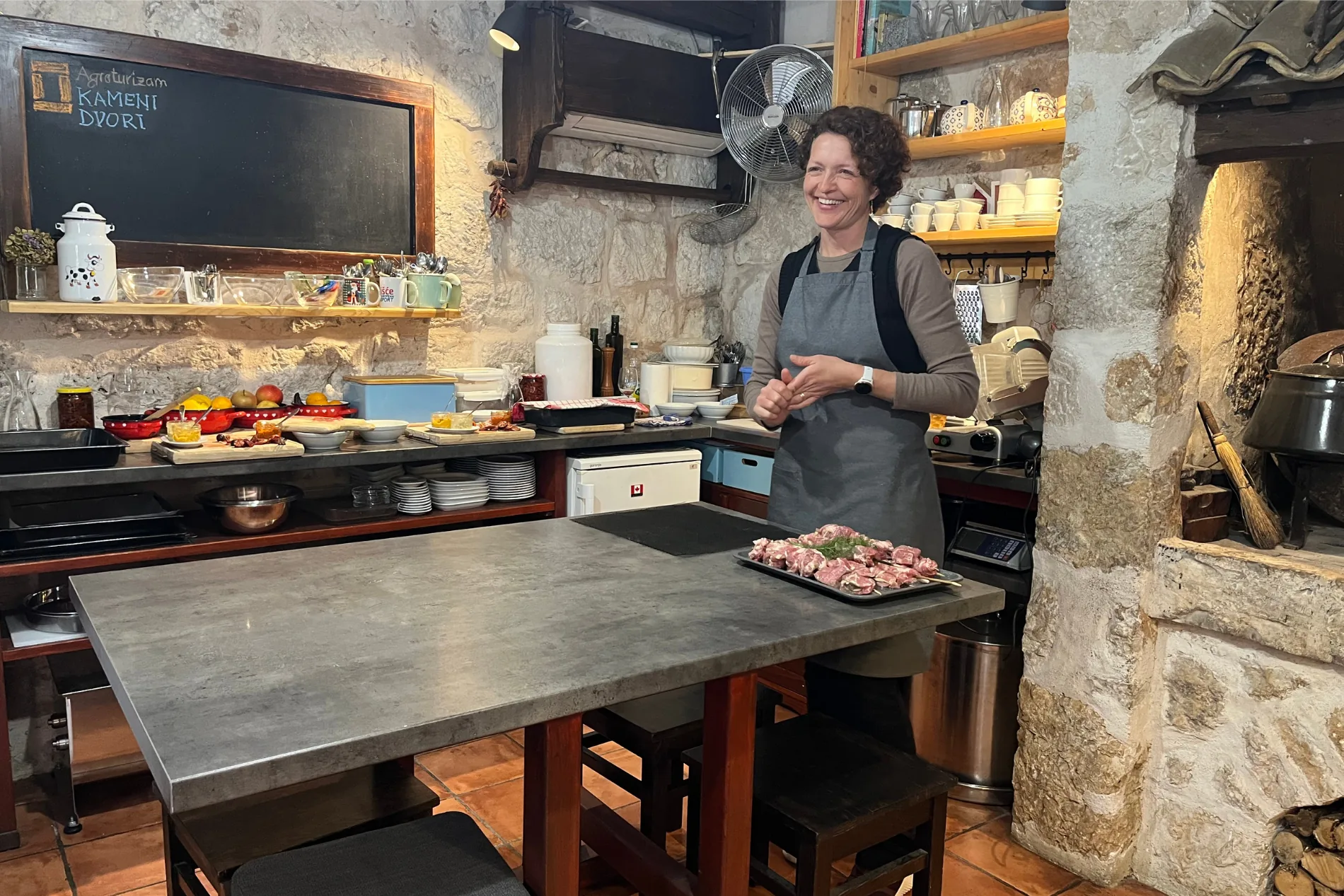 A local host welcoming guests in a stone kitchen